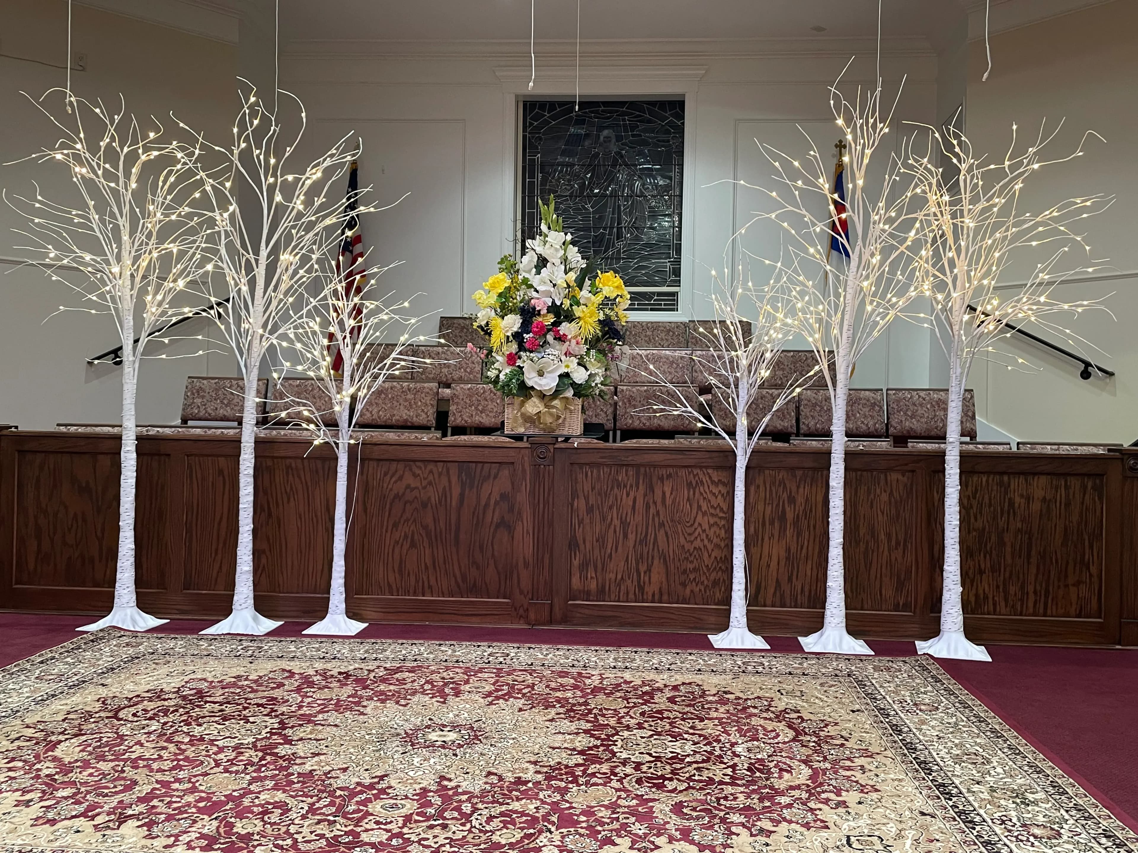 Vibrant floral centerpiece at the base of decorative white birch trees