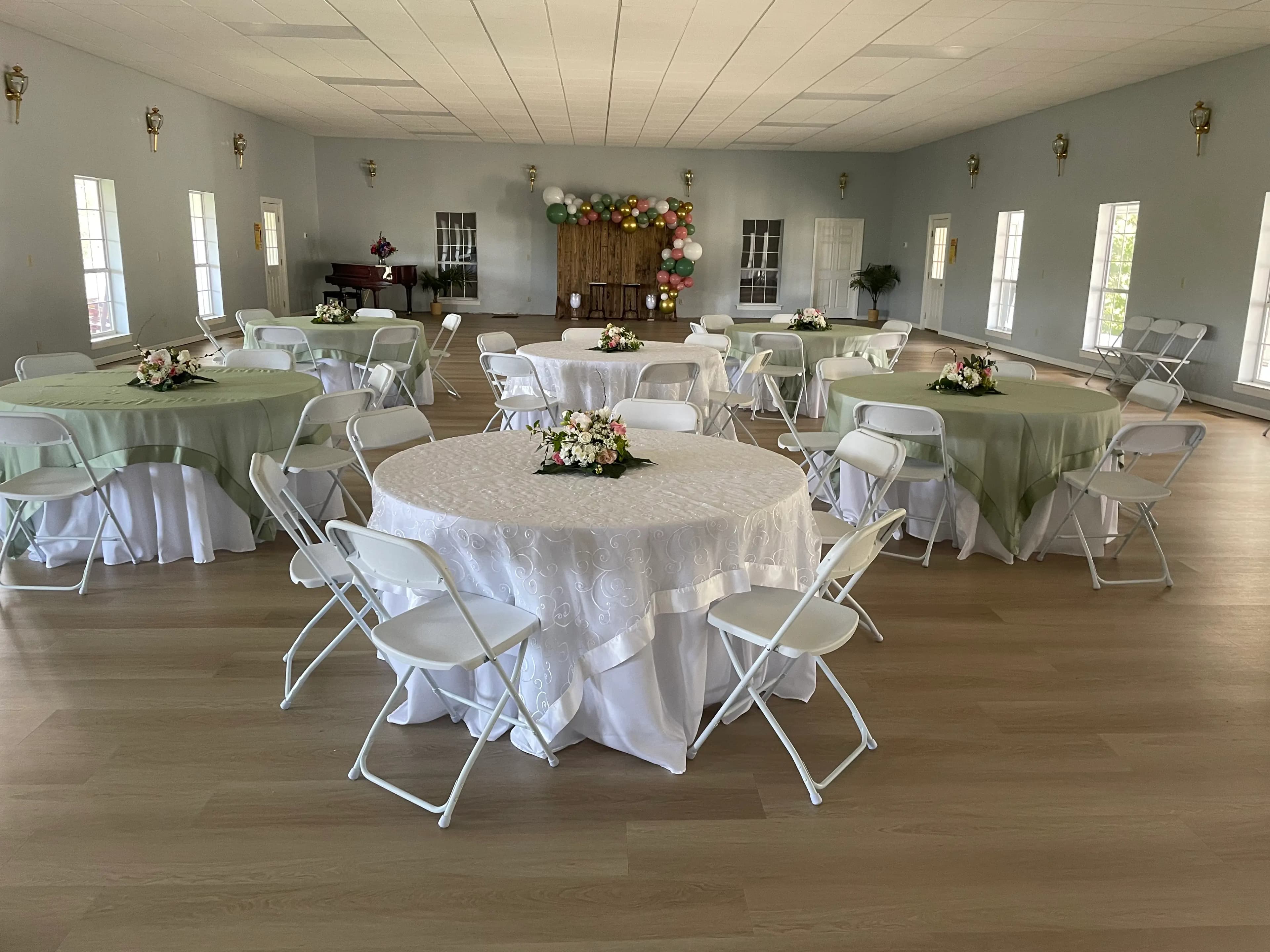Indoor bridal shower setup with floral centerpieces and balloon arch