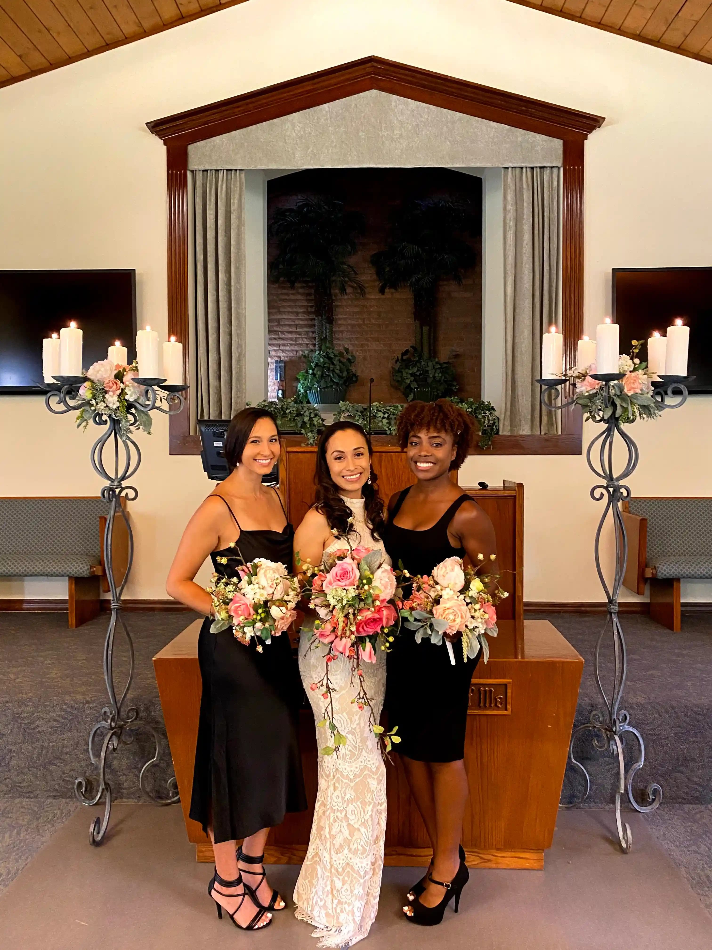 Ornate candelabras with elegant floral arrangements flank women holding lush rose bouquets in a formal setting.
