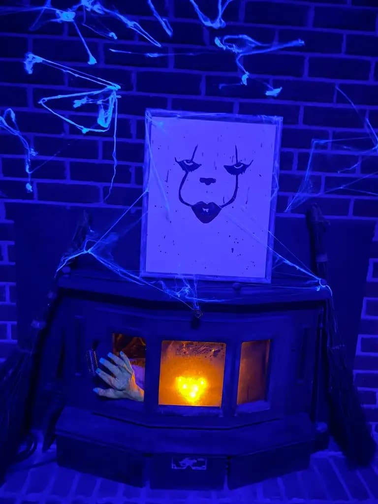 Halloween fireplace in storytelling room with lit spiderwebs and Pennywise picture